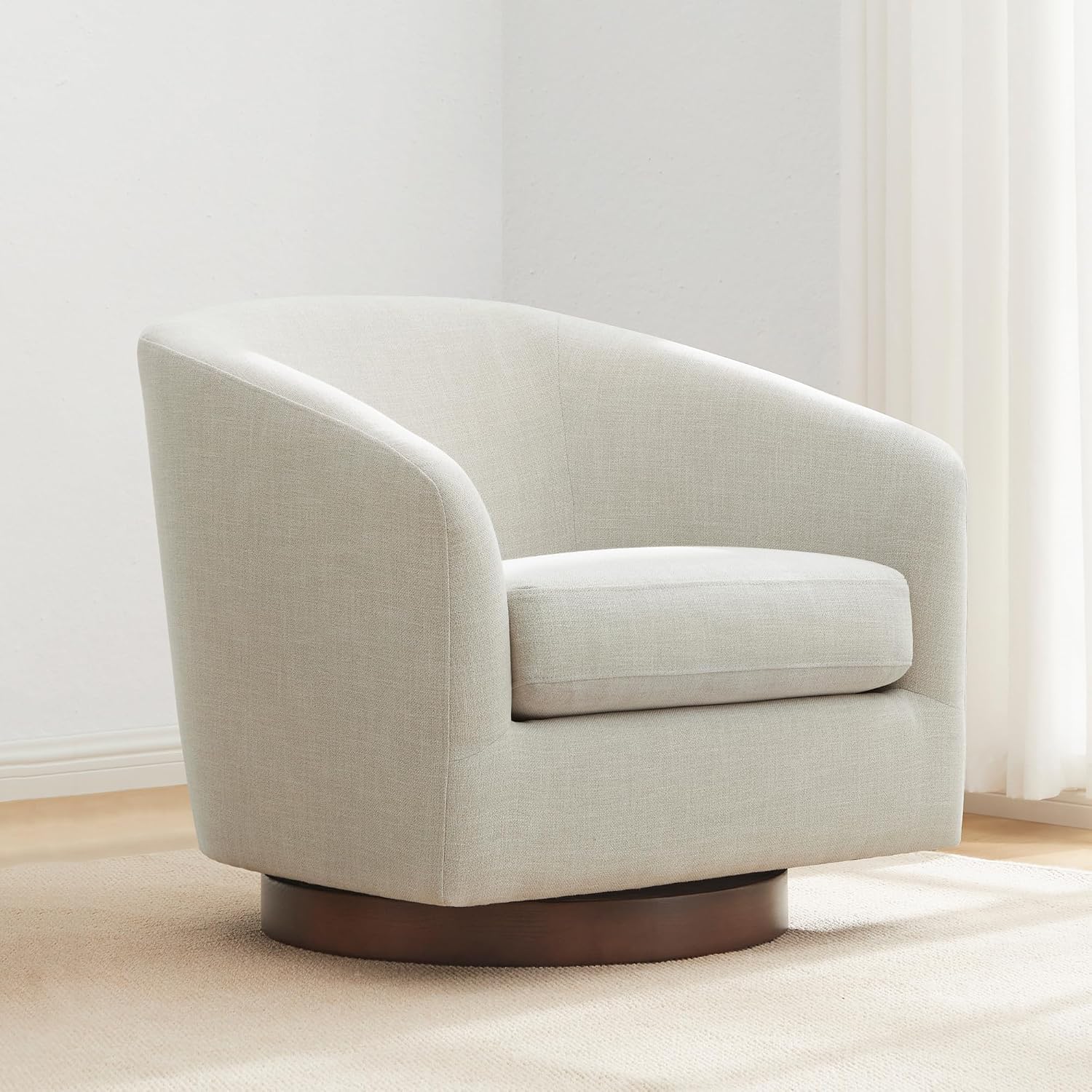 CHITA swivel barrel accent chair in light linen on a round dark wood swivel base in a bright corner