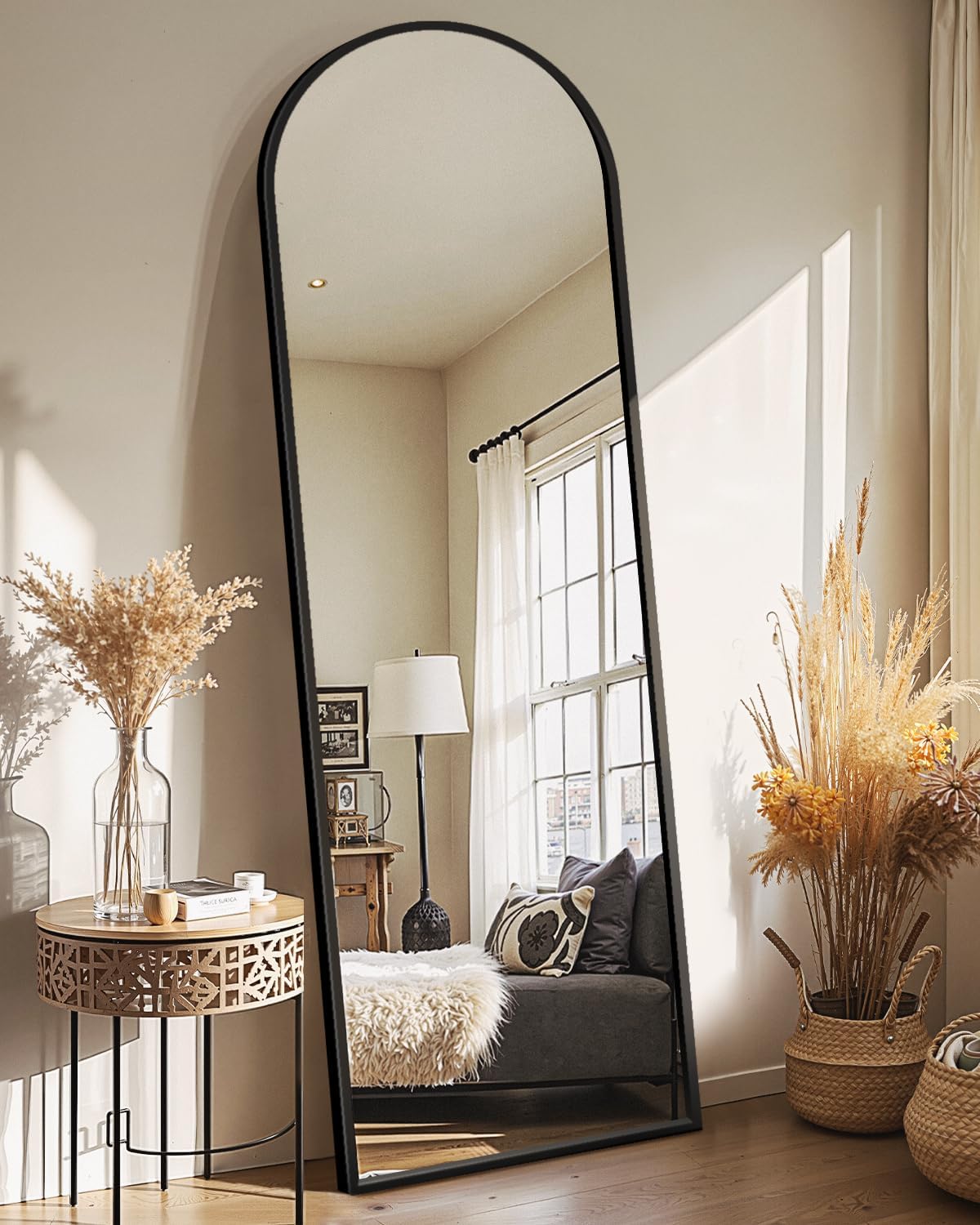 Delma narrow arched full length mirror with black frame and stand leaning in a warm entryway corner