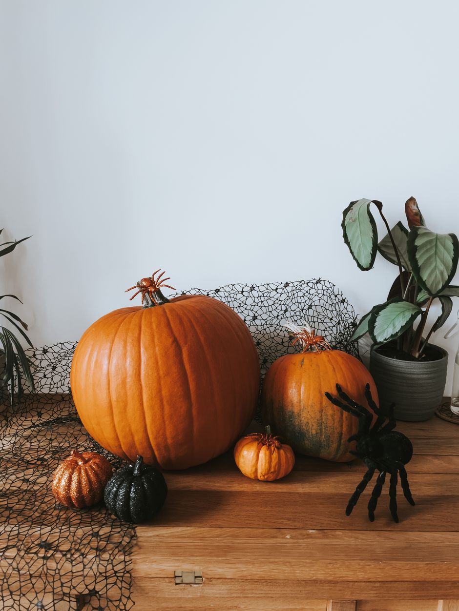 Pumpkins and black spider webbing styled on a wooden console for halloween mantel decor