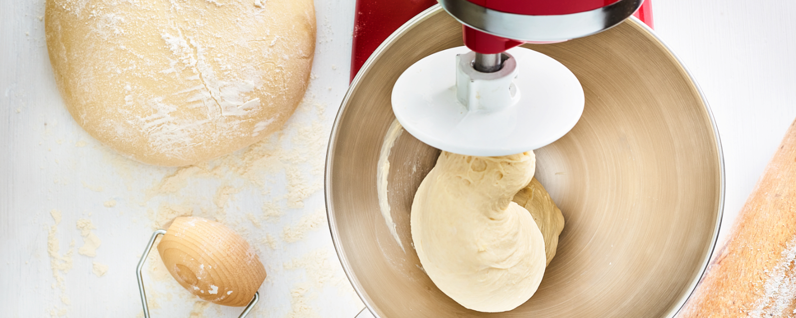 Stand mixer kneading bread dough in a steel bowl
